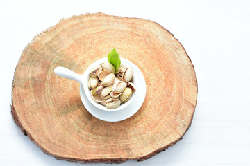  Pistachios on the white wooden background, accompanied by green leaf