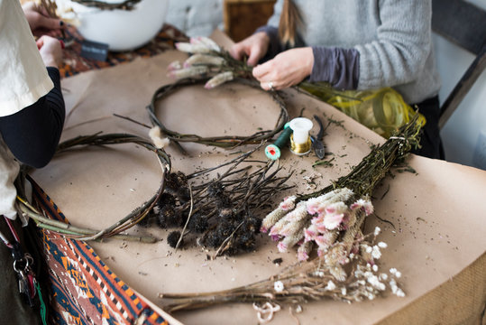 Women making decorative  wreath from foraged branches and dried flowers