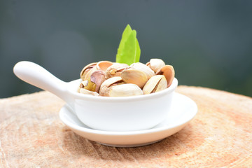  Pistachios on the white wooden background, accompanied by green leaf