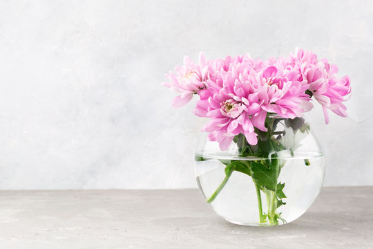 Pink flowers in a glass vase on a light grey table. Background for Valentine Day, Mothers Day or Birthday. Space for text.