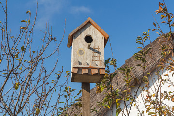 Wooden birdhouse on a thatched roof background.