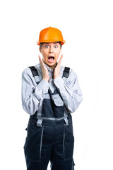 Young woman in uniform and helmet, worker, foreman surprised and scared. the specialist opened his mouth in surprise. the girl is terrified. isolated