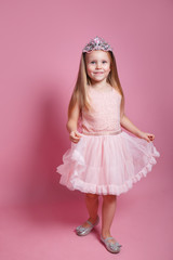 Funny little girl with long blond hair in a tulle skirt and princess sparkling crown © Elena Kratovich
