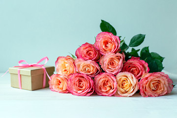 bouquet of roses and gift box on a wooden background, festive decoration 