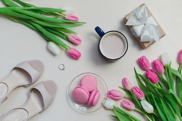 Obraz na płótnie Canvas Coffee cup, spring tulip flowers and pink macarons on pastel table top view. Greeting for Womans or Mothers Day