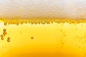 Light beer in a glass, macro photo. Above is foam. Abstract background image of a drink.