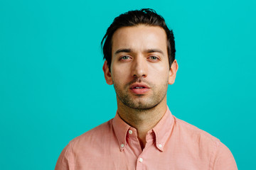 Portrait of a young adult man serious, looking forward, isolated on blue studio background