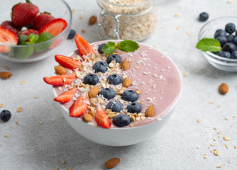 Healthy Breakfast bowl: berry cocktail with strawberries, blueberries, banana, almonds, granola and mint.