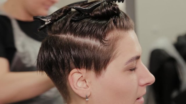 Professional hairdresser woman doing hairstyle on wet hair to client.