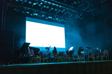 White screen and music stands, microphones at concert stage
