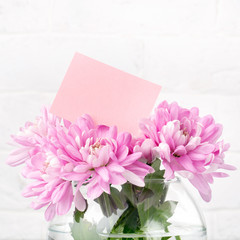 Pink flowers with card in a glass jar on white. Background for Valentine Day, Mothers Day or Birthday. Space for text.