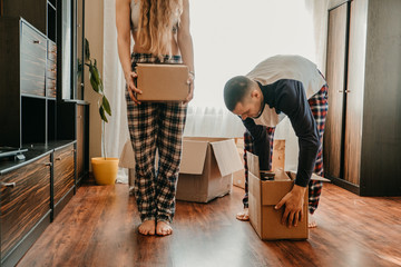 Moving day. Happy couple in their new apartment is having fun with cardboard boxes. Cheerful young couple in new house at moving day