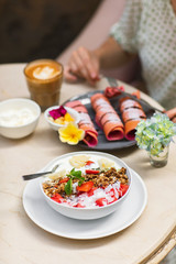 Sweet, vegan and healthy breakfast at Bali cafe. Bowl of homemade granola with yogurt and fresh berries on marble table.