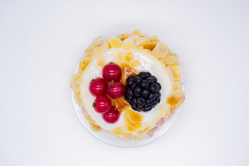 Close up of a сream cake with almond petals, red currants and blackberries. Concept of holiday, birthday, sweet life, Valentine's day