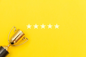 Simply flat lay design winner or champion gold trophy cup and 5 stars rating isolated on pink pastel background. Victory first place of competition. Winning or success concept. Top view copy space.