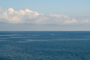 Obraz premium The black sea is blue with a blue sky and a white cloud and two barges floating on the horizon.