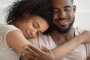 Close up african couple embracing closed eyes enjoy tender moment