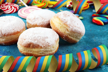 Carnival powdered sugar raised donuts with paper streamers. German berliner or krapfen for carnival
