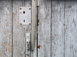 Texture of an old wooden vintage door with peeling gray paint and an old doorknob. Background old wood door