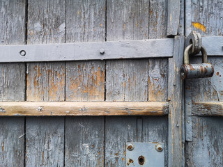 Texture of an old wooden vintage door with peeling gray paint and an old door lock. Background old wood door