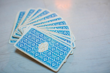 Tarot cards in fortune teller hand on white wooden table background. Future reading.