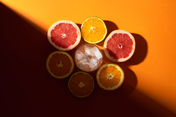 Citrus fruits and glass with ice in sunlight. Making cold drink