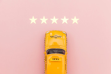 Yellow toy car Taxi Cab and 5 stars rating isolated on pink background. Smartphone application of taxi service for online searching calling and booking cab concept. Taxi symbol. Copy space.