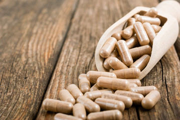 herbal plants and medicine capsules on old wooden