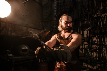 Portrait of a brutal muscular blacksmith standing in the workshop