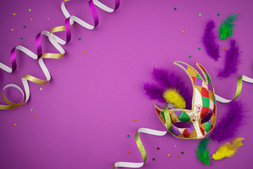 Festive, colorful mardi gras or carnivale mask and accessories over purple background. Party...