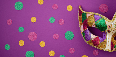 Banner with colorful mardi gras or carnivale mask and accessories over purple background. Party...