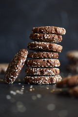 Healthy vegan snack. Pile of chocolate gluten free sesam seed cookies on black background