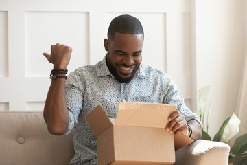 Happy african guy opening long-awaited parcel box