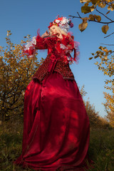 Obraz na płótnie Canvas Sensual blond girl in fantasy red fairy tale stylization in apple park.