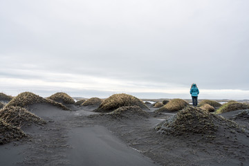 Obraz premium Girl with blue jacket are standing on a sand dune in Stokksnes looking at the view. Icelandic and travel concept.