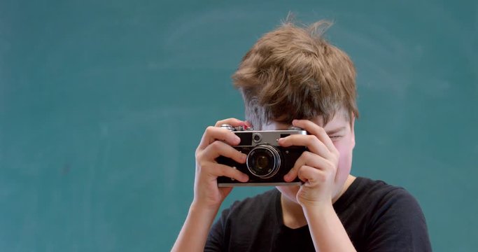 A boy with blue eyes cockes the camera shutter and takes a picture