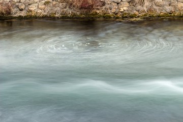 Abstract, long exposure shapes of the streaming river water with a whirlpool