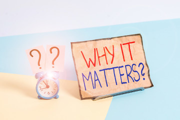 Writing note showing Why It Matters Question. Business concept for most important thing to be done when involved in situation Alarm clock beside a Paper sheet placed on pastel backdrop