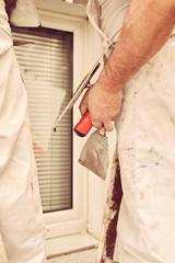 Construction workers plaster a wall.