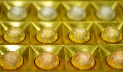 top view of Chocolate Candies In A Gold wrappers and gold Gift Box