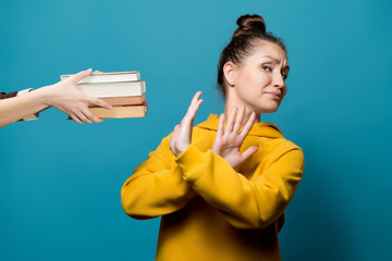 young girl in a yellow sweatshirt on a blue background refuses books