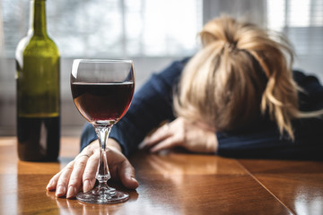 Drunk woman sleeping on table after drinking wine. Alcohol addiction concept - obrazy, fototapety, plakaty