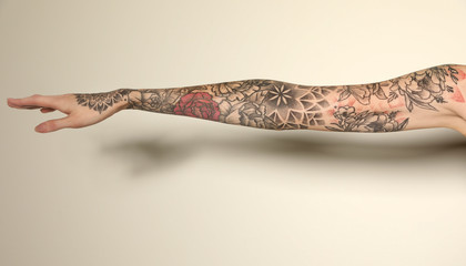 Woman with colorful tattoos on arm against white background, closeup - obrazy, fototapety, plakaty