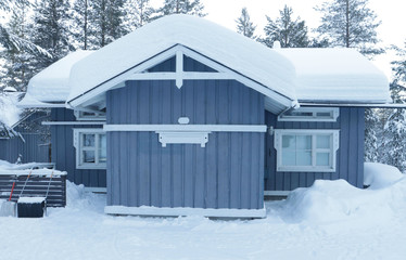 Wooden, snow-covered gray house in a forest in Lapland. Comfort, silence, snowy winter, country life