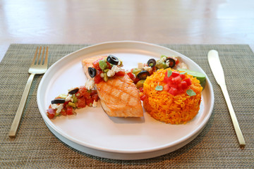 Plate of grilled salmon steak with Mediterranean salsa and saffron rice
