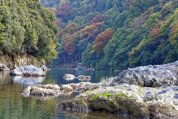 Fototapeta na wymiar Beautiful river and a forest with red and green maple leaves during autumn in Arashiyama, Japan