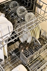 Washed dishes in a warm light in extended dishwasher baskets at an angle.