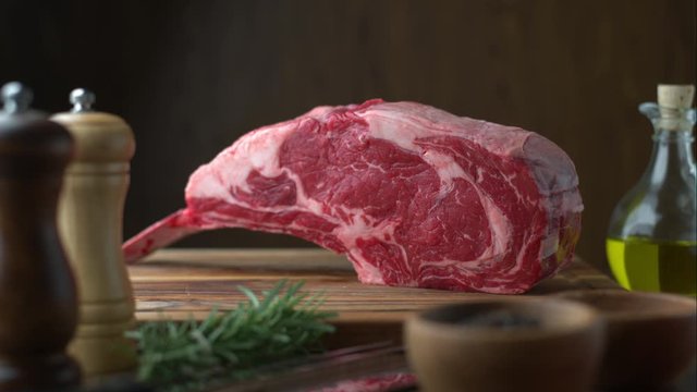 fresh raw tomahawk steak on wooden cutting board