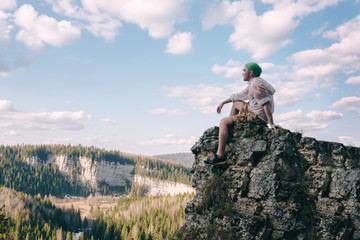 Young hiker sitting and relaxing on top of a mountain