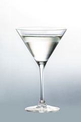 Thin glass goblet filled with martini isolated on neutral background